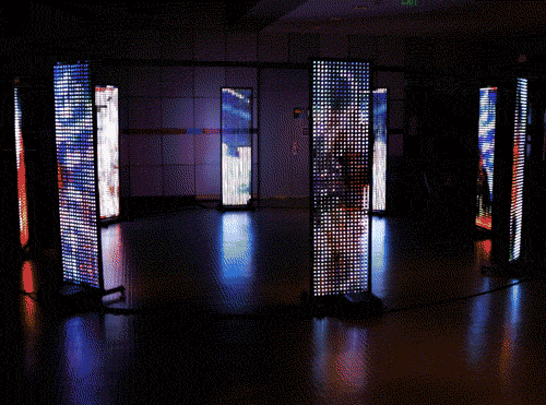 alt="8 LED screens in a circle displaying colorful abstract content"